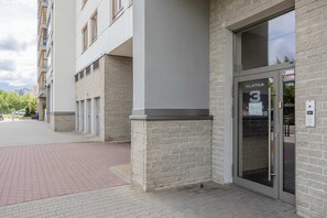 A modern building entrance with a glass door labeled 'KLATKA' and a security keypad. - Stylish apartment with a balcony in Warsaw, close to the airport by Noclegi Renters (Warszawa)