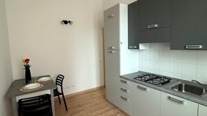 Una cucina compatta con zona pranzo, dotata di fornello a gas, lavandino e arredamento moderno.