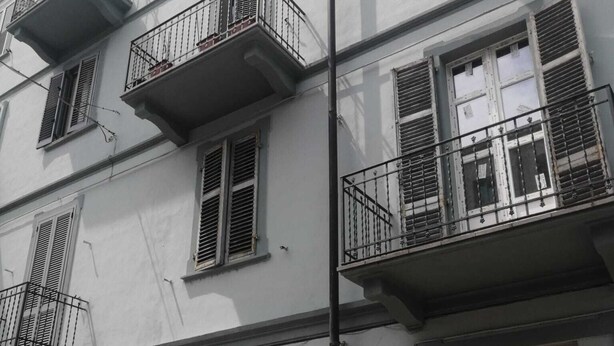 Un edificio a più piani con balconi, una porta e una telecamera di sicurezza.