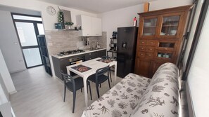 Cocina compacta con mesa, sillas y refrigerador.