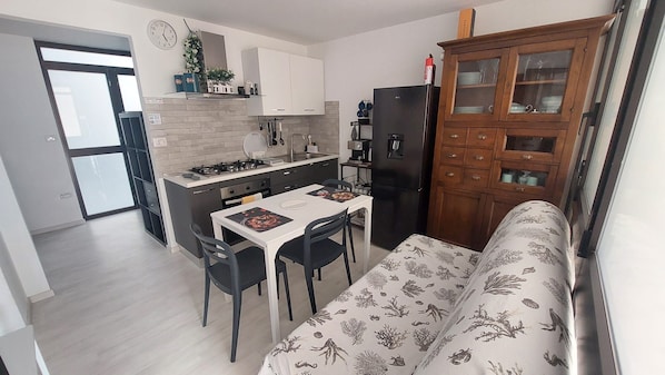 Una cucina compatta con un tavolo da pranzo, sedie e un frigorifero.
