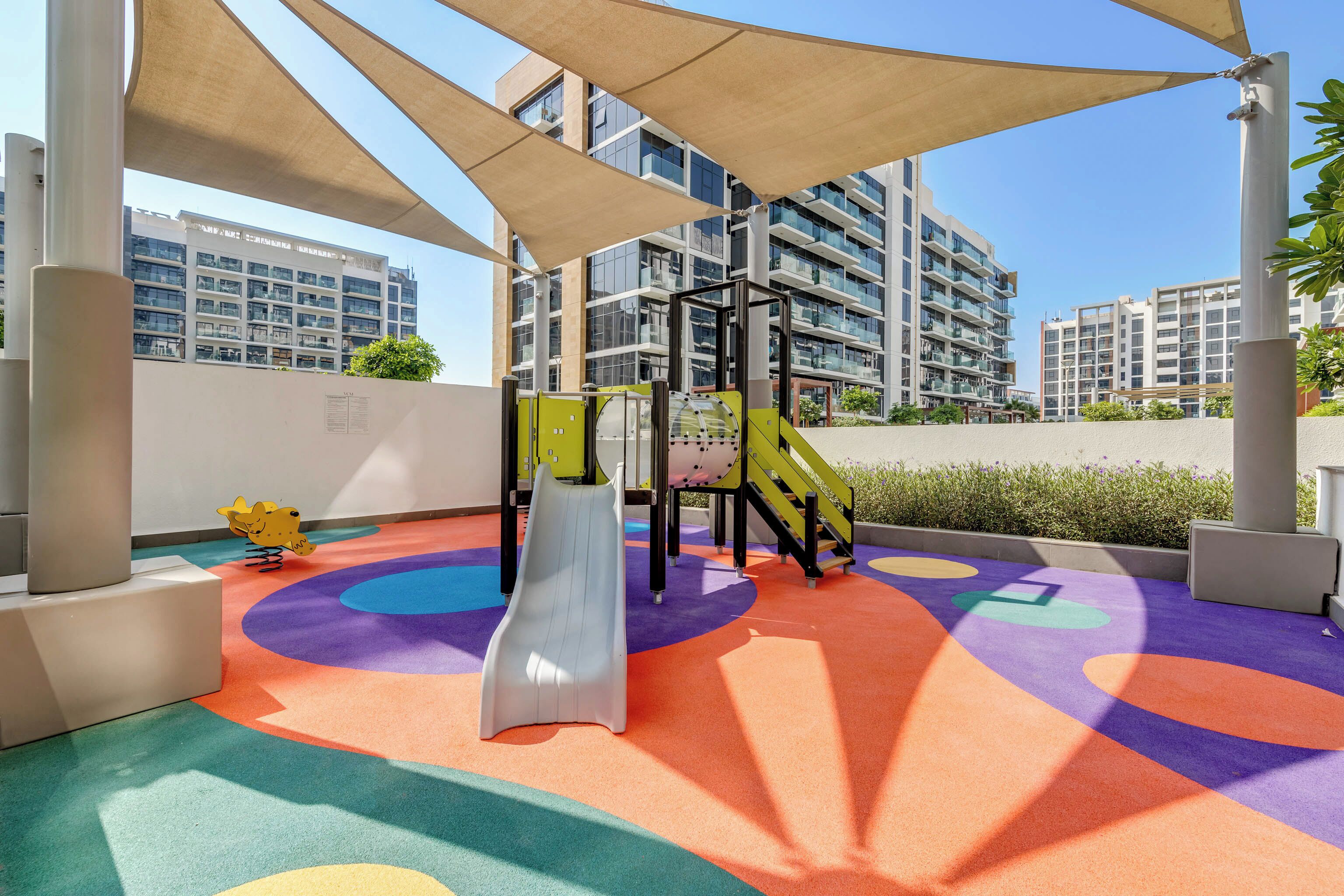 Un parque infantil con un tobogán, estructuras de escalada y marcas de colores en el suelo.