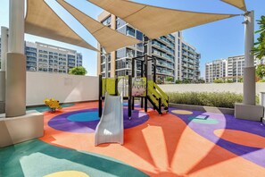 Un parque infantil con un tobogán, estructuras de escalada y marcas de colores en el suelo.