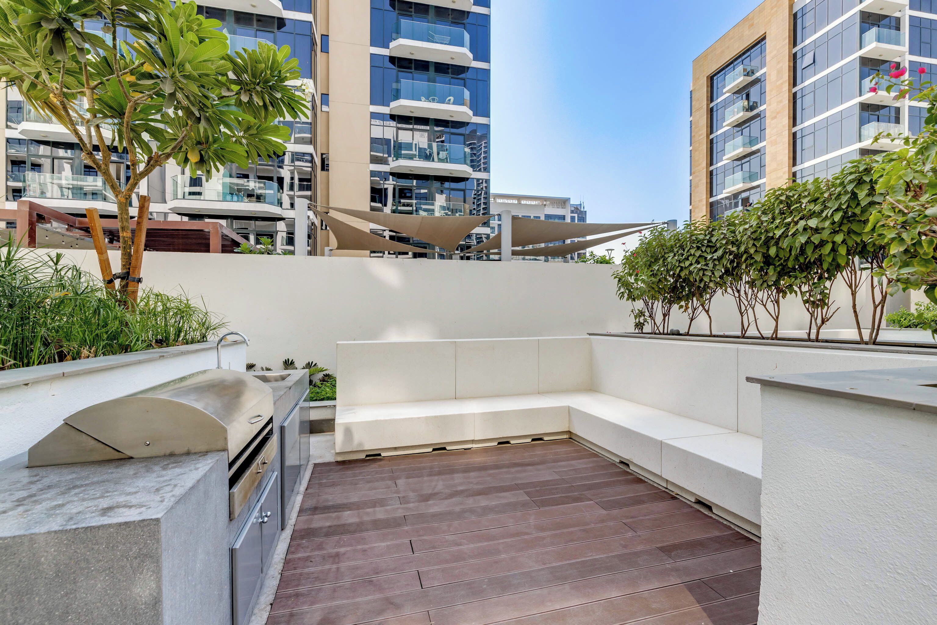 Terraza en la azotea con una parrilla, zona de estar y vistas de edificios circundantes.