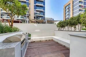 Terraza en la azotea con una parrilla, zona de estar y vistas de edificios circundantes.
