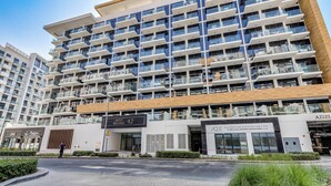 A multi-story residential building with balconies, a ground-level commercial area, and a clear sky. - GlobalStay Azizi Riviera 42 (Dubai)