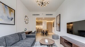 A modern living room with a grey sofa, a coffee table, and a TV on the wall. - GlobalStay Azizi Riviera 42 (Dubai)