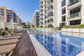 Ein modernes Wohngebäude mit Dachpool, Liegestühlen und blauem Himmel.