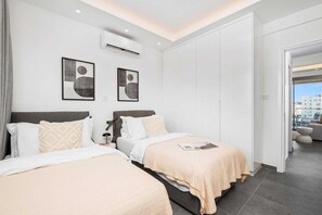 Ein Hotelzimmer mit zwei Betten, einem großen Fenster und Blick auf die Stadt.