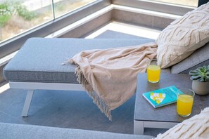 Ein modernes Zimmer mit gepolstertem Sitz, einem Orangensaftglas, einem Buch und einer Topfpflanze.