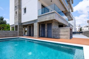 A modern residential building with a swimming pool, balconies, and a clear sky. - The Emblem Residence by Nomads (Paphos)