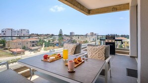 Ein Balkon mit Frühstückstisch, Grill und Blick auf die Stadt.