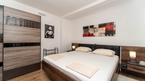 A modern bedroom with a large bed, bedside tables, a wardrobe, and artwork on the walls. - Beachfront apartment 1 - Dramalj by Villas Guide (Crikvenica)