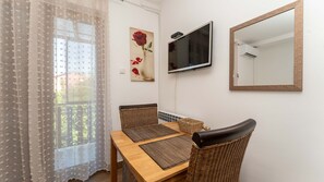 Ein Essbereich mit Tisch, Stühlen und einem an der Wand befestigten Fernseher.