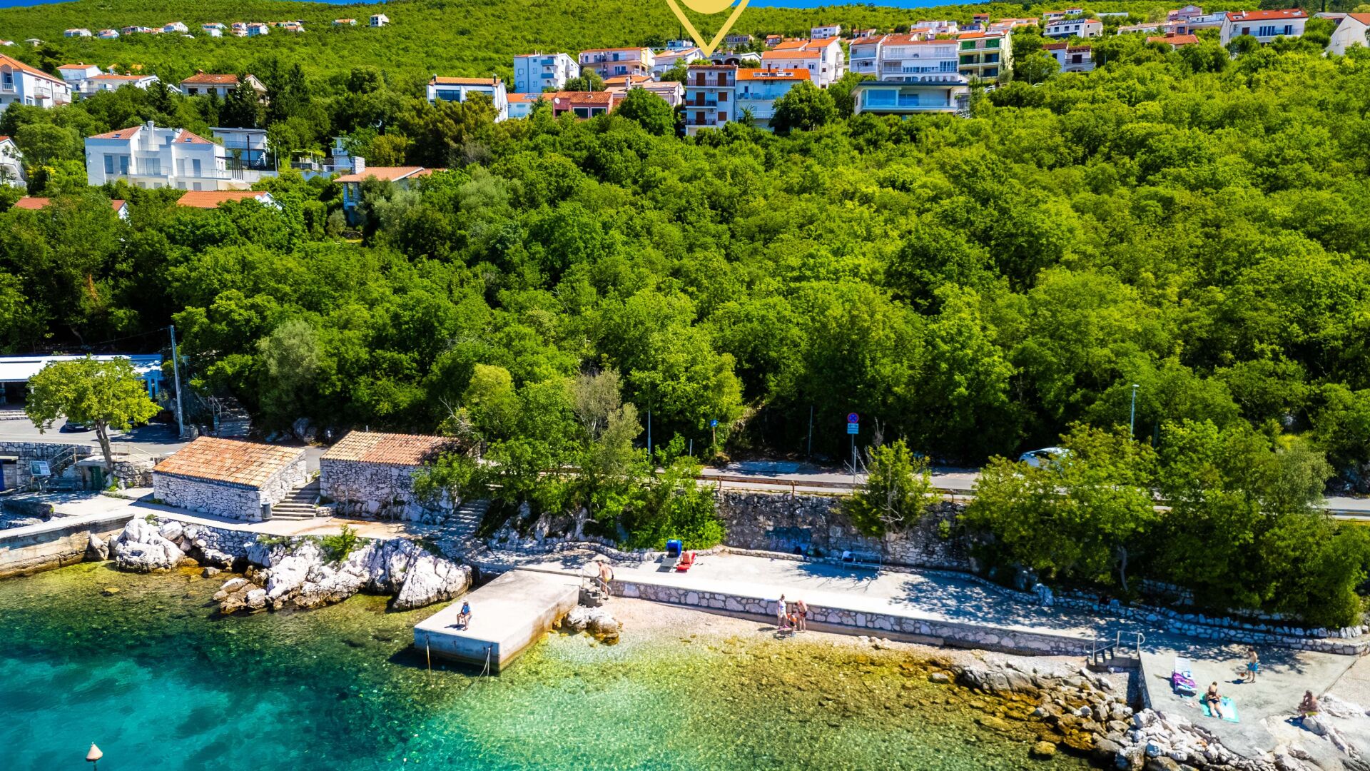 Eine Küstenstadt mit freiem Blick auf das Meer, einer Steinmole und Gebäuden mit roten Dächern.