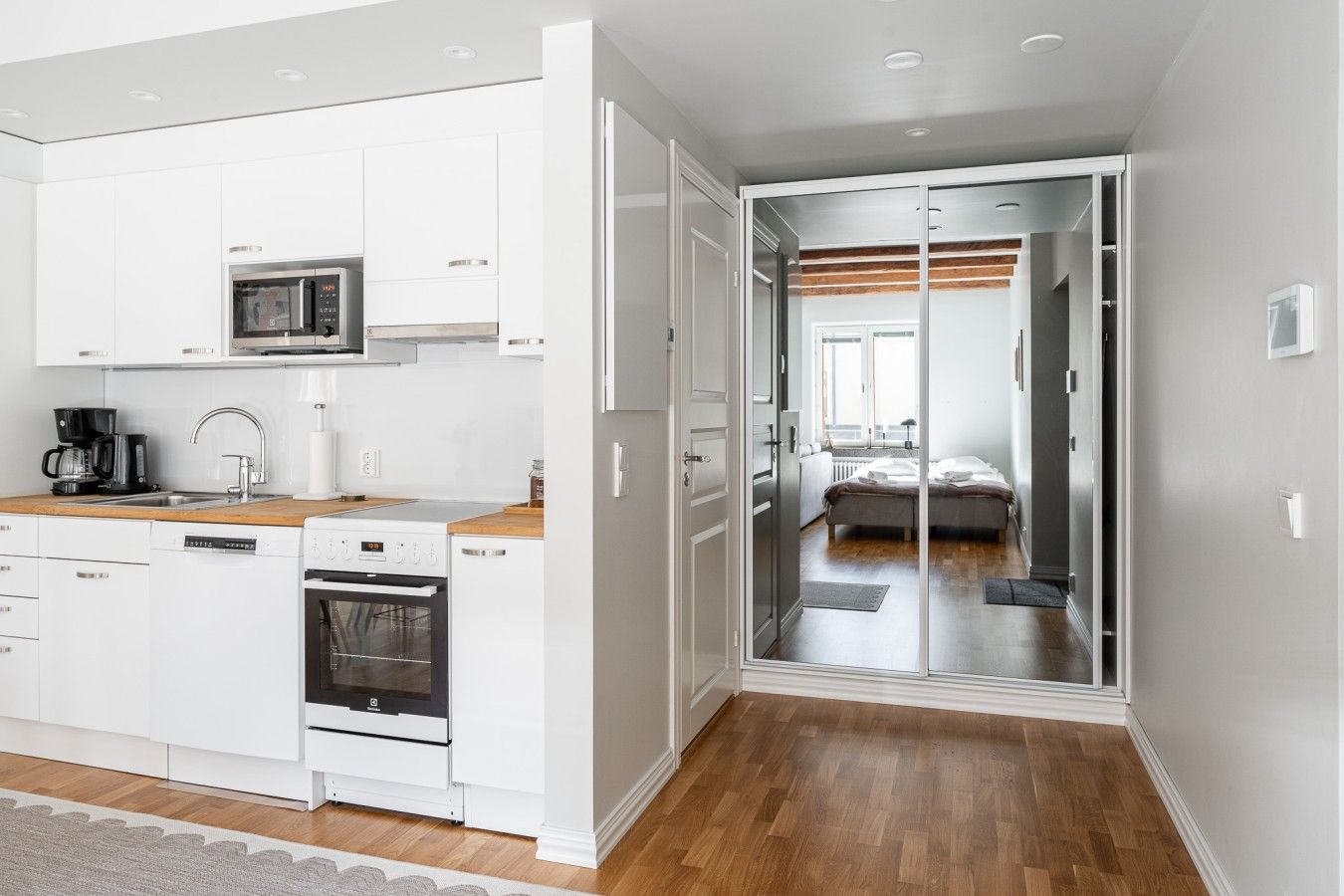 A compact kitchen with white cabinets, a microwave, a coffee maker, and a dishwasher.