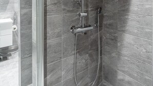 A modern shower with a glass enclosure, a handheld showerhead, and a wall-mounted faucet. - Main Square Studio with Free Parking (Tampere)