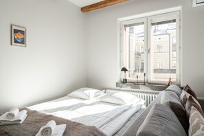 A bedroom with a bed, a window, a radiator, and a framed picture on the wall. - Main Square Studio with Free Parking (Tampere)
