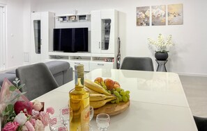Ein Essbereich mit einem Tisch für zwei Personen, einer Olivenölflasche und einer Obstplatte.