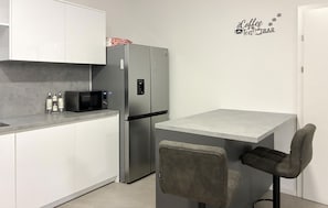 A compact kitchen with a refrigerator, microwave, and a small table with two chairs. - Lovely home in Milcetici (Milcetici)