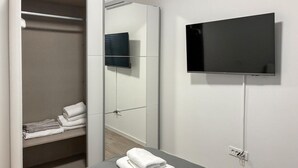 Ein Hotelzimmer mit Bett, Wandfernseher, Schrank und Handtuchhalter.