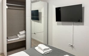 Ein Hotelzimmer mit Bett, Wandfernseher, Schrank und Handtuchhalter.