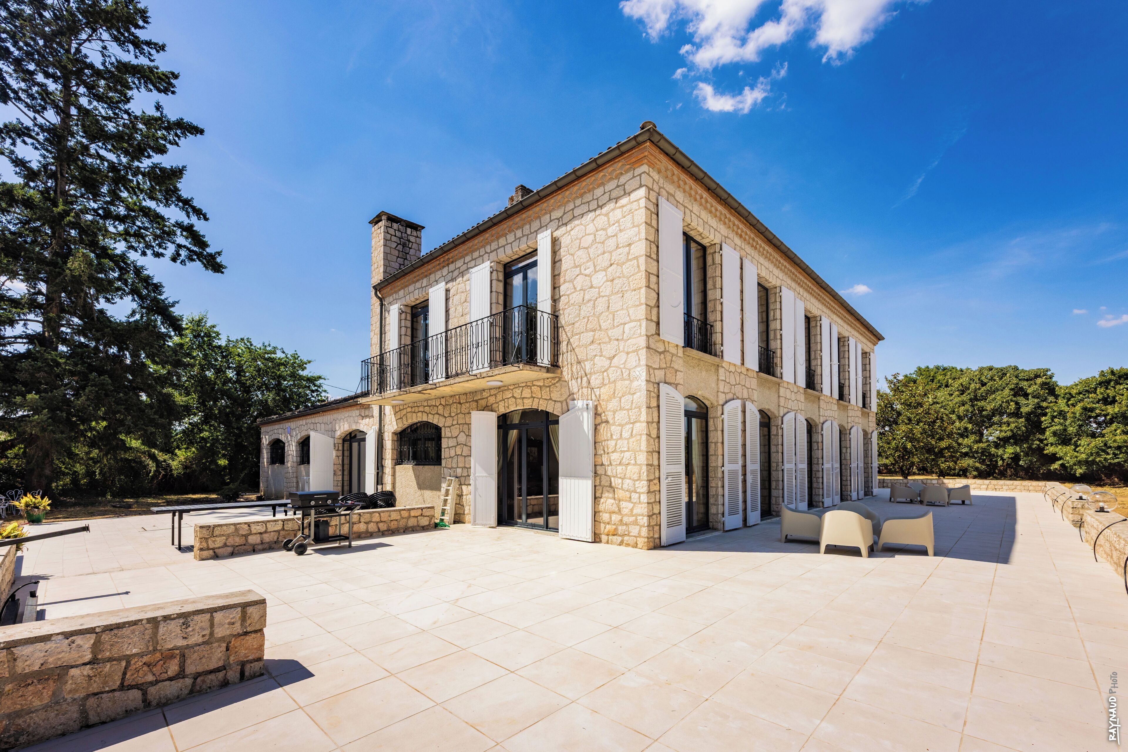 A stone building with a balcony, outdoor seating, and a clear sky.