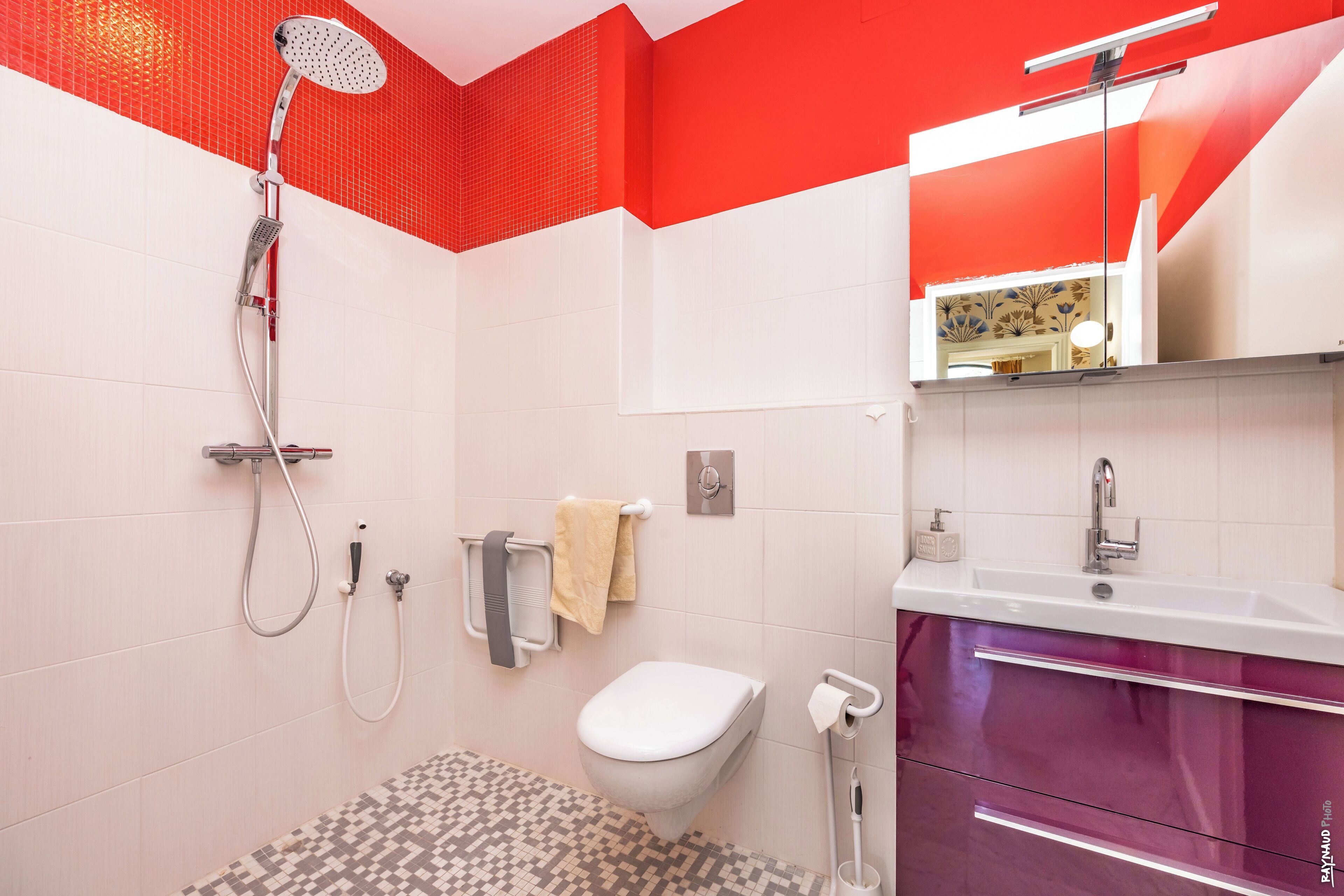 Uma casa de banho moderna com chuveiro, sanita e lavatório.