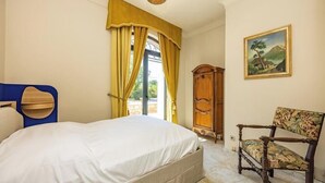 Une chambre à coucher avec un lit, une chaise, une armoire et un tableau au mur.