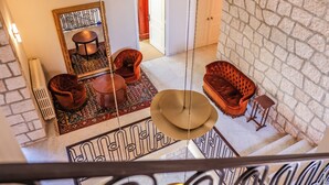 Une pièce aux hauts plafonds, dotée d’un sol à motifs, d’un grand miroir et d’un coin salon avec un canapé et des fauteuils.