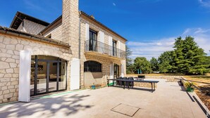 Un bâtiment en pierre doté d’un balcon, d’un espace extérieur aménagé pour s’asseoir et offrant une vue sur un ciel dégagé.
