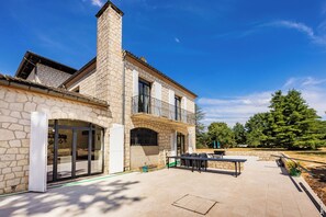 Un bâtiment en pierre doté d’un balcon, d’un espace extérieur aménagé pour s’asseoir et offrant une vue sur un ciel dégagé.