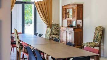 Une salle de conférence avec une longue table, des chaises, un buffet et une vue sur l’extérieur, visible à travers une porte.