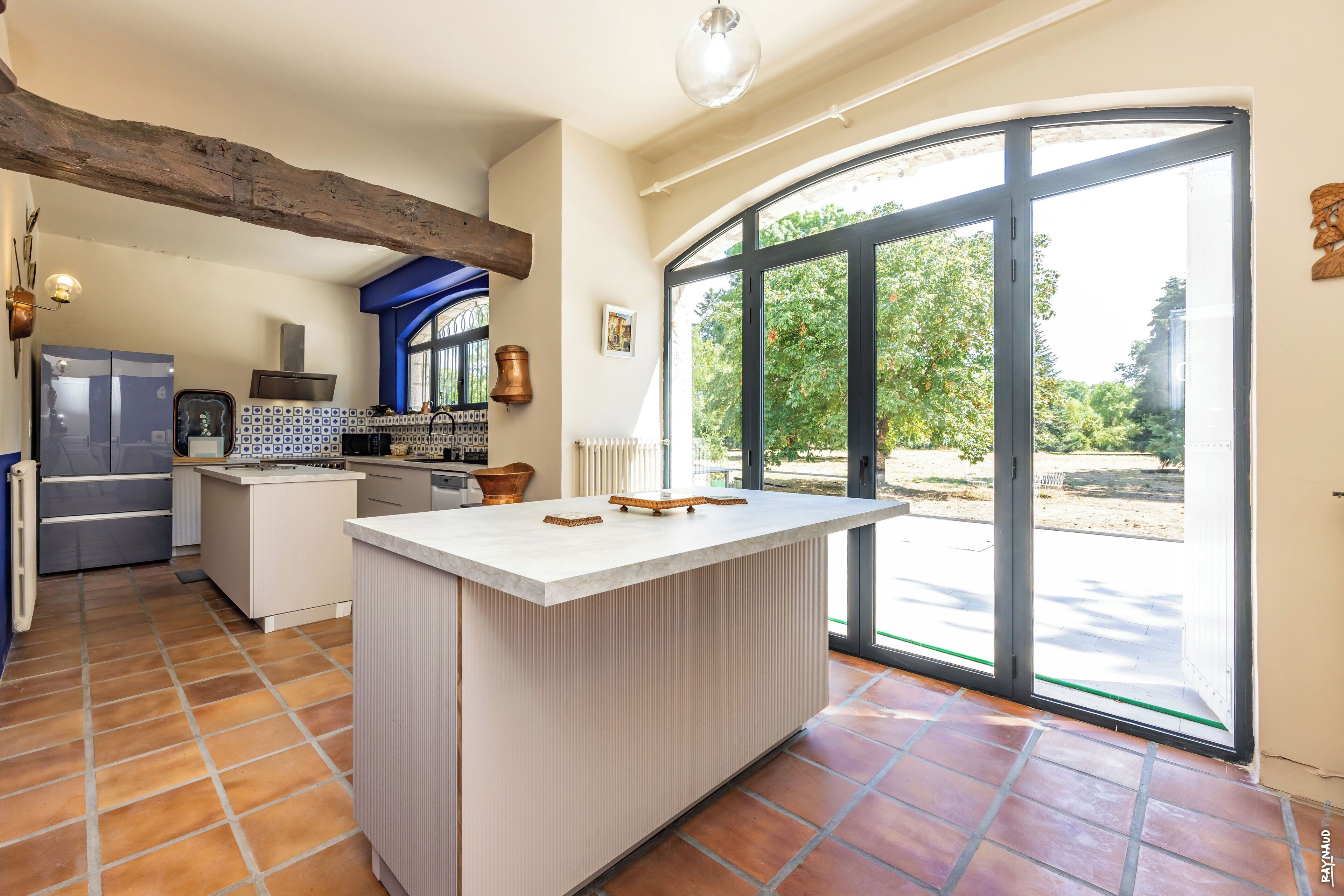 Una cocina con una isla central, horno empotrado y un ventanal grande.