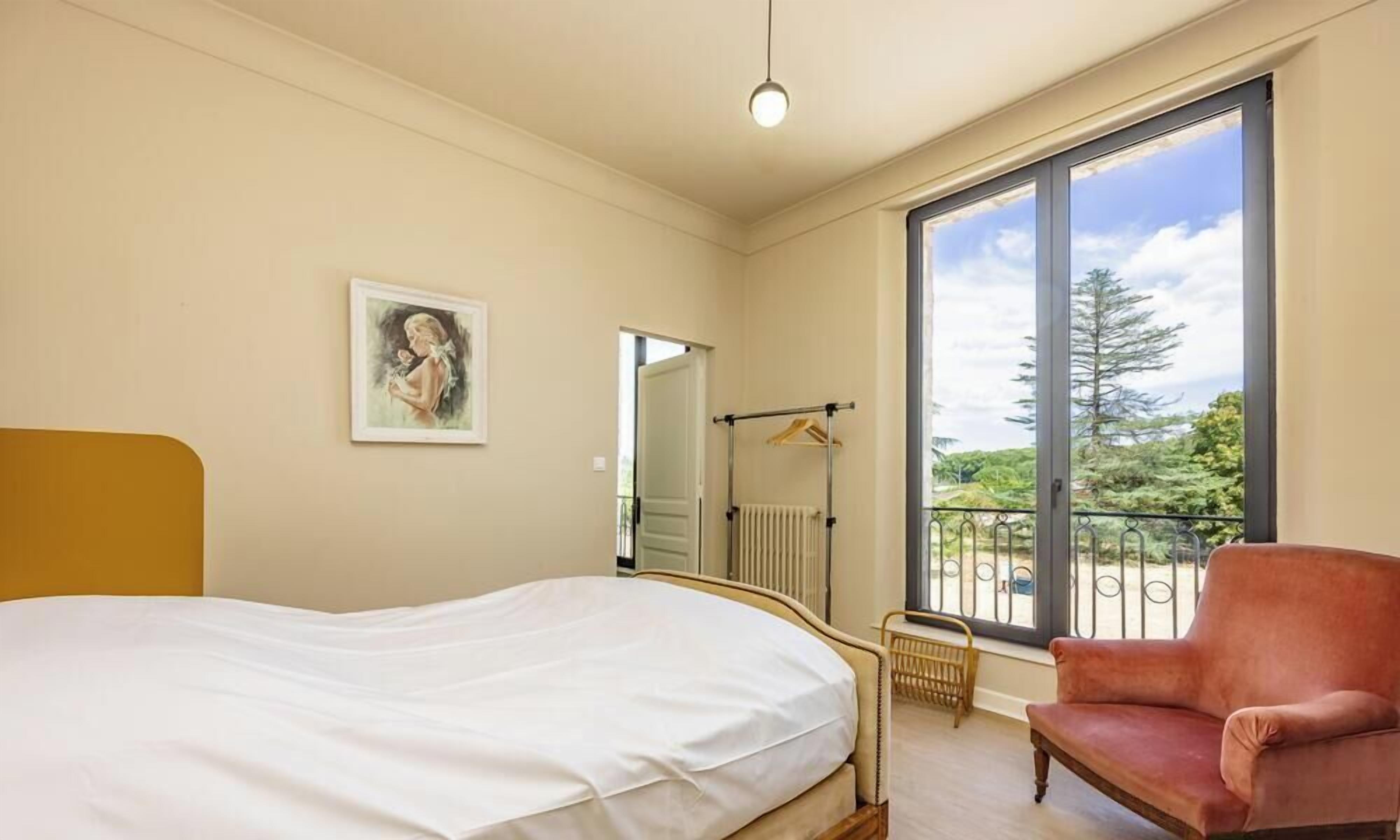 Une chambre à coucher avec un lit, une chaise, une fenêtre donnant sur un beau paysage et un radiateur.
