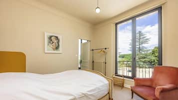 Une chambre à coucher avec un lit, une chaise, une fenêtre donnant sur un beau paysage et un radiateur.