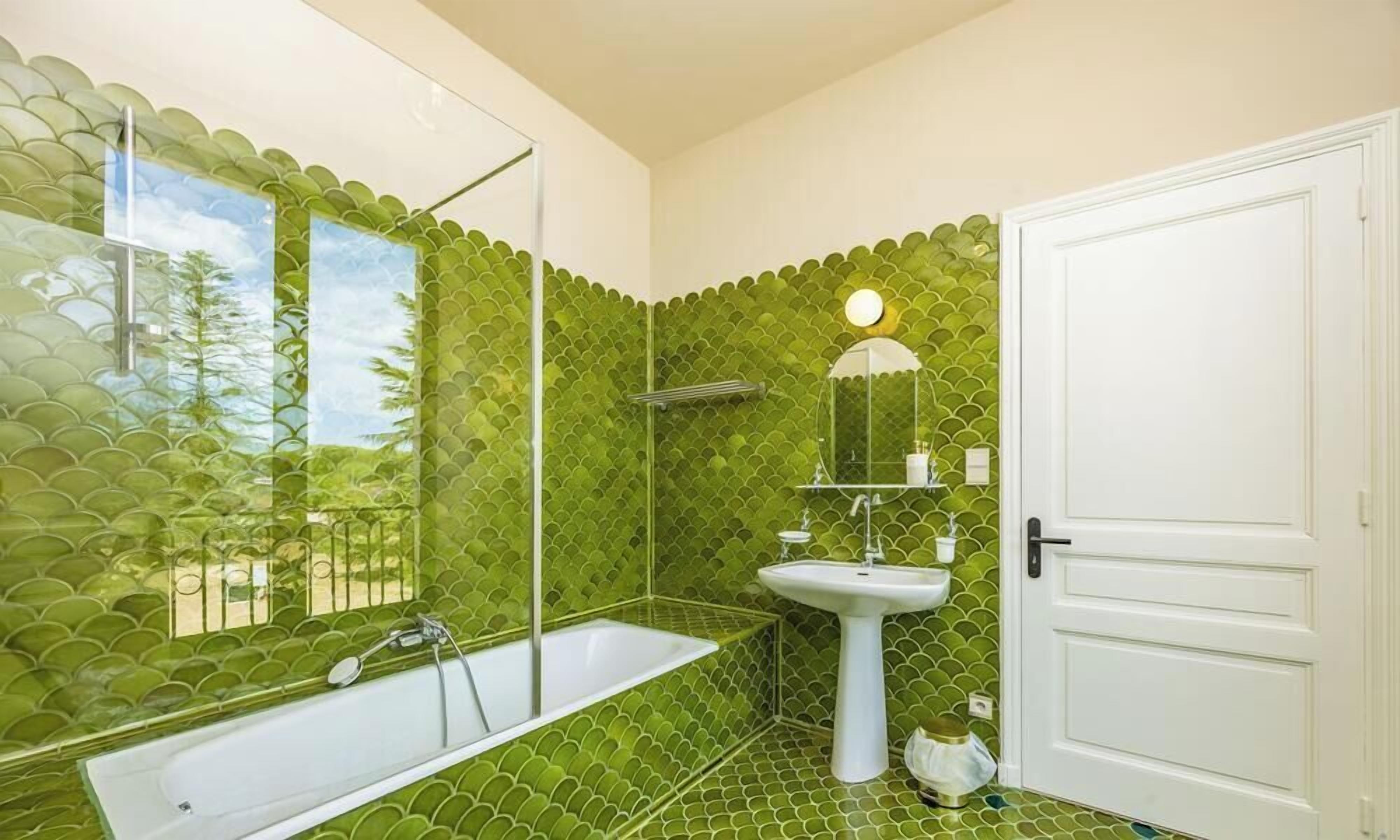 A bathroom with a bathtub, a sink, and a mirror.
