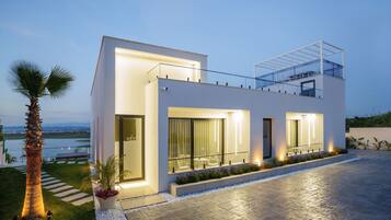 A modern two-story house with a balcony, large windows, and a well-maintained garden.