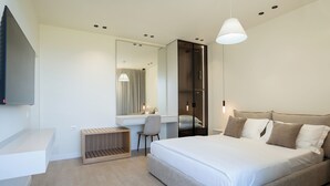 Ein modernes Hotelzimmer mit einem großen Bett, einem Schreibtisch, einem Stuhl und einem Kleiderschrank.