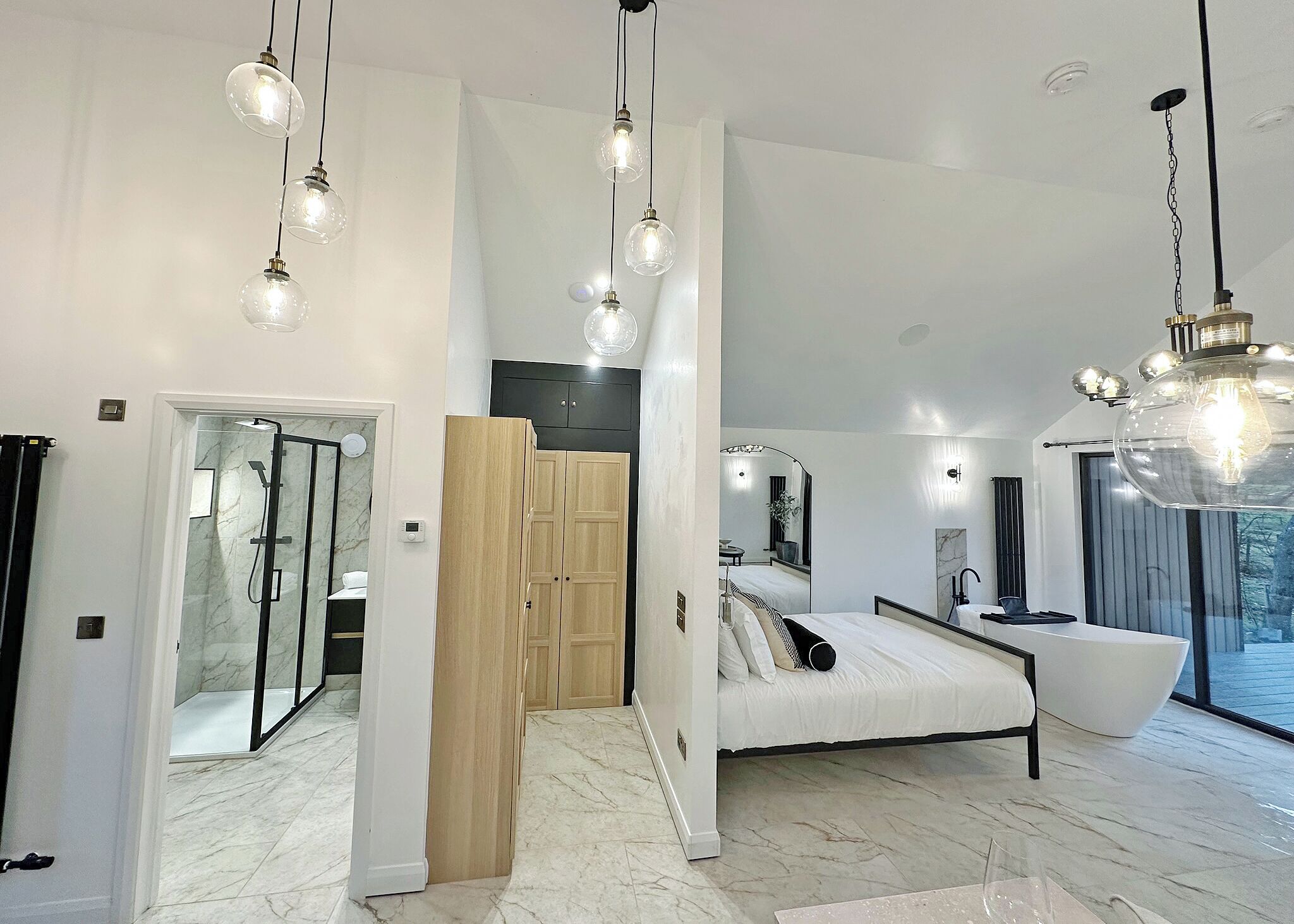Ein modernes Schlafzimmer mit Bett, Nachttisch und großem Fenster.