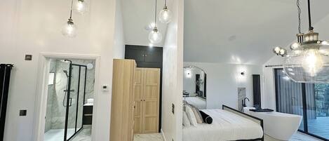 Un dormitorio moderno con cama, mesita de noche y un ventanal grande.