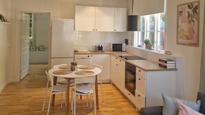 Una cucina moderna con mobili bianchi, un tavolo da pranzo con sedie e un forno integrato.
