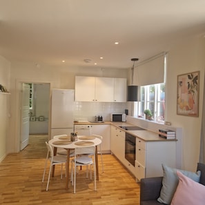 Une cuisine moderne avec des meubles blancs, une table à manger avec des chaises et un four encastré.