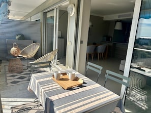 Une terrasse extérieure avec une table à rayures, des chaises en osier et un coin repas comprenant des chaises et une table.