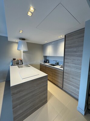 A modern kitchen with a central island, built-in appliances, and a wooden accent wall. - Apartment 'D&L Sea View' with Private Terrace, Wi-Fi and Air Conditioning (Cannes)