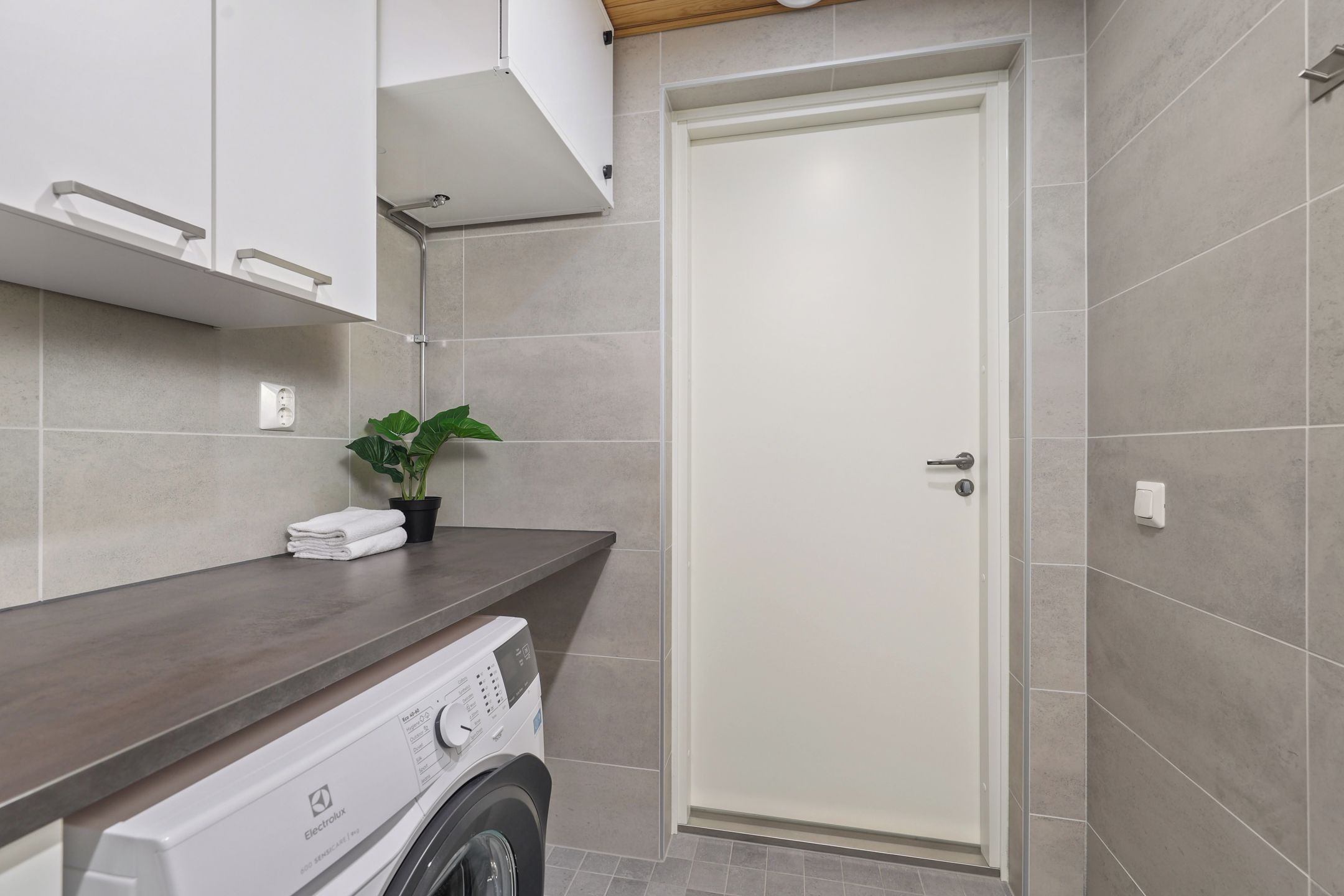 Un baño moderno con lavadora, toallero y una planta en maceta.