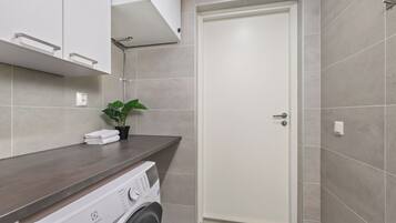 Un baño moderno con lavadora, toallero y una planta en maceta.