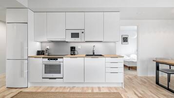 A modern kitchen with white cabinetry, a built-in oven, a coffee maker, and a sink.