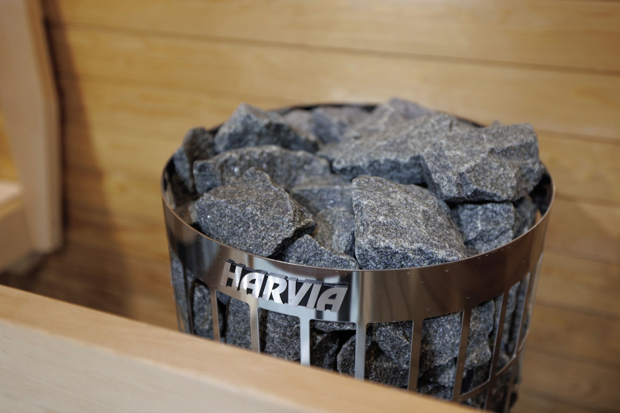 A metal container labeled 'HARVIA' filled with gray rocks.