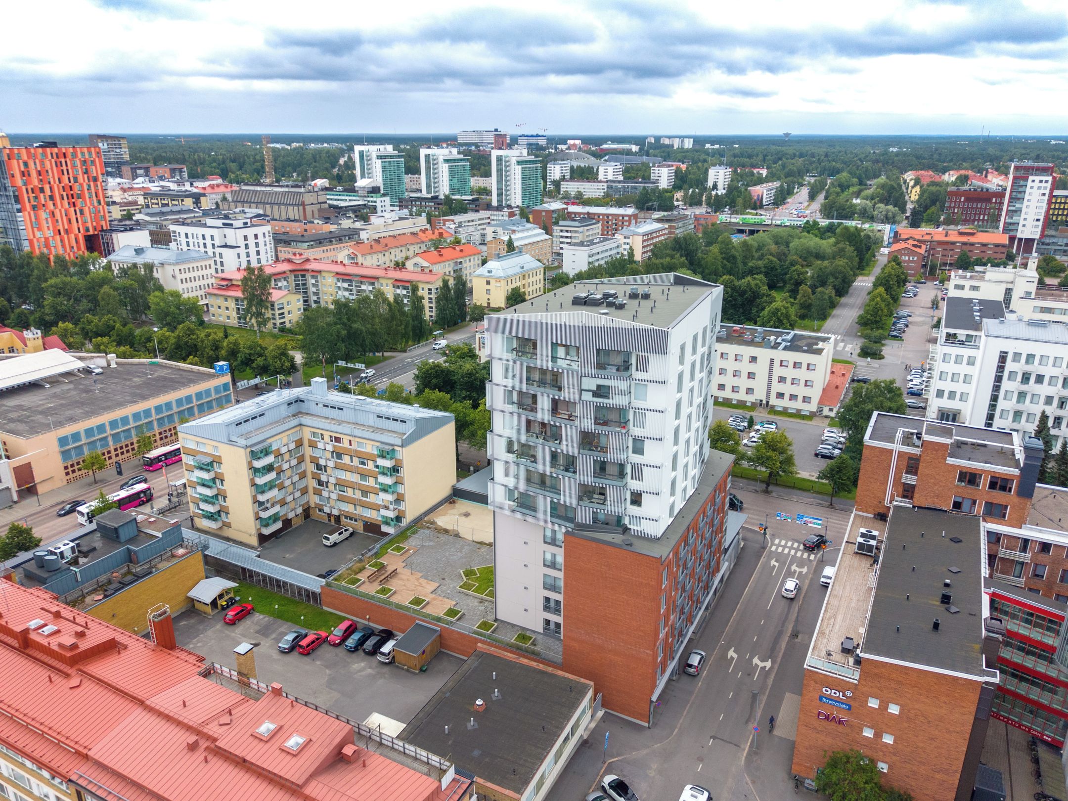 A cityscape with modern buildings, a parking lot, and a road.